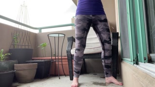 girl wetting grey leggings outside on the balcony