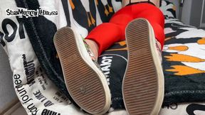 Brunette Crossed Legs in Yoga Pants lying on sofa in Stinky Shoes - Sniff the Smell of Stinky Boots, Sweaty Insoles in Sneakers, Girl Ignores Smoking, Pointing long Toes with Black Pedicure