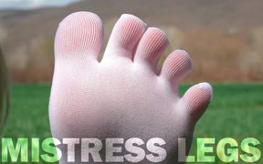 Feet in Cute White Socks with Jeans on the Grass Field