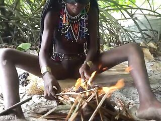 Glamorous tribe hotty making traditional jewelery next to a firecamp