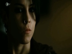 Noomi Rapace lying on her stomach on a bed, her hands and