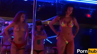 Women in fishnets and bikinis compete in a booty shake contest under neon lights