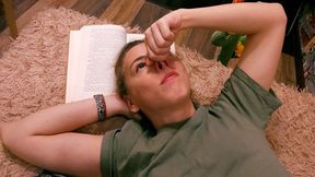 Girl is scratching her nose while reading a book