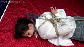 Rosa: cleave-gagged topless brunette barefoot girl in jeans shorts and unbuttoned white shirt, hogtied with hemp rope, rolls and wiggles on the bed (HD WMV)