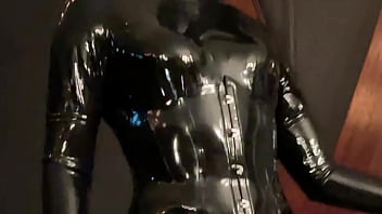 Transgender dominatrix in latex catsuit, gas mask and thigh high boots.